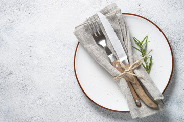 White plate and cutlery on stone table top view. 