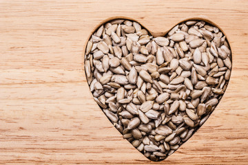 Heart shaped sunflower seeds on wood surface
