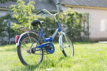 Fototapeta na wymiar children's bicycle on the grass. Blue teen bike on a green lawn in the yard