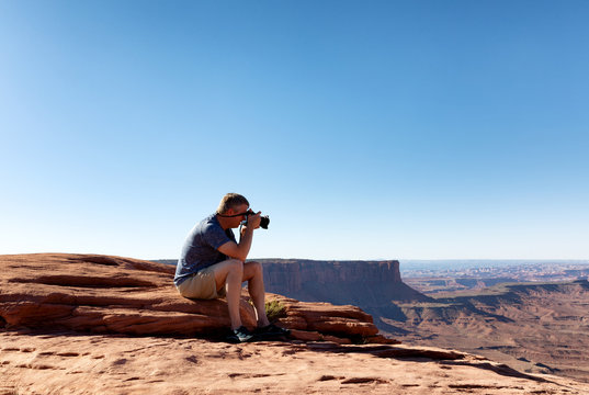 Mature man taking photos of the Grand Canyon while sitting down
