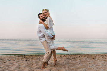 Fototapeta na wymiar groom hugging laughing beautiful bride on beach