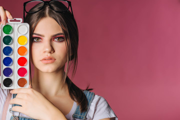 portrait of a girl painter with a palette of colorful paintings in an art studio. Thoughtful artist, creative mood. Art. Painting. Design.Creative. Hobby. Watercolor