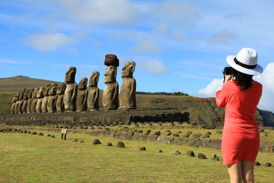 Female tourist taking pictures of the famous Moai statues at Ahu Tongariki on Easter Island, Chile, South America