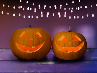 holidays, halloween and decoration concept - close up of carved pumpkins on table over ultra violet background