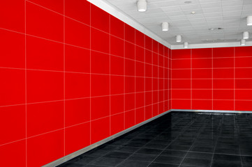 Big empty room interior with bright red wall, whire ceiling and dark floor. New office space. Tiles on the wall and floor.