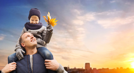 family, childhood and fatherhood concept - happy father carrying son with autumn maple leaves over...