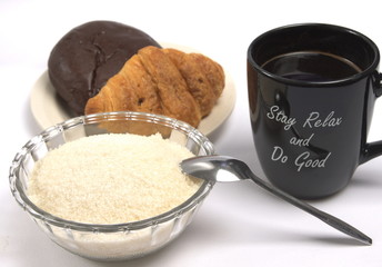 A cup of black coffee, a bowl of sugar and a plate of pastry on an isolated background