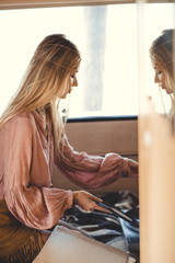 blonde hippie girl putting vinyl record into player inside camper van