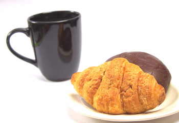 A cup of black coffee and a plate of pastry on an isolated white background