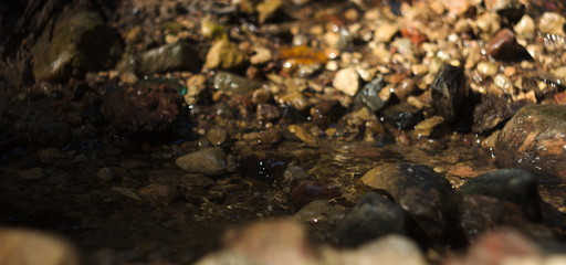 Water stream flowing through rocks with rocks in background