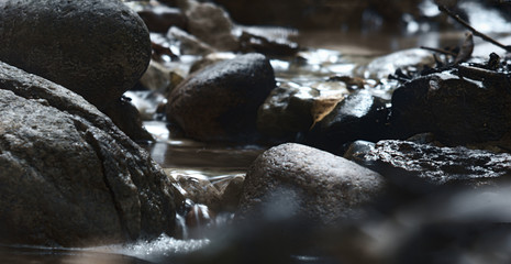 Naklejka na ściany i meble Small stream flowing through rocks taken with long exposure