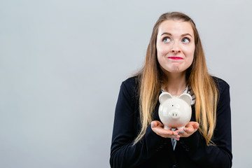 Fototapeta na wymiar Young woman with a piggy bank on a gray background