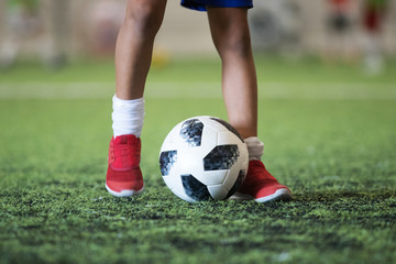 Traditional soccer ball on soccer field grass with young player feet