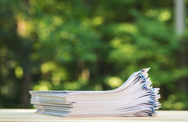 A stack of documents on a shiny green forest background