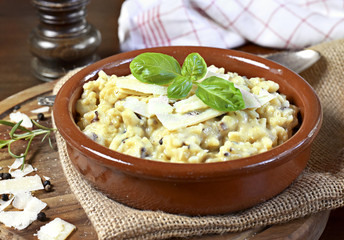 Delicious risotto dish in a brown bowl, with mushrooms and parmesan cheese. Risotto a la milanese, close up shot.