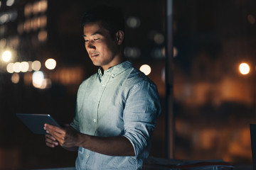 Asian businessman using a tablet late at night © mavoimages