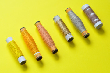 Fototapeta premium yellow thread reels for sewing on a yellow background. photo thread on. threads of shades of yellow. sewing, needlework, handmade. Use for backgrounds, wallpapers, posters, advertisements, card