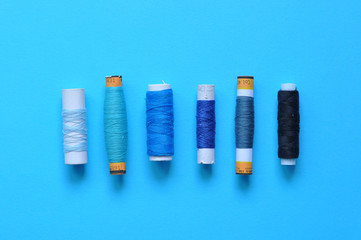 blue thread reels for sewing on a blue background. photo thread on. threads of shades of blue. sewing, needlework, handmade. Use for backgrounds, wallpapers, posters, advertisements, card