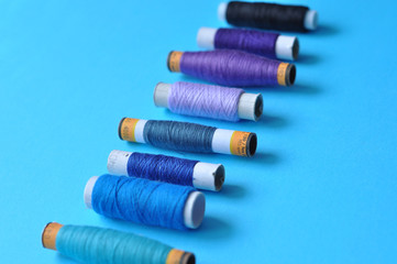 blue thread reels for sewing on a blue background. photo thread on. threads of shades of blue....