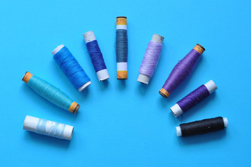 blue thread reels for sewing on a blue background. photo thread on. threads of shades of blue. sewing, needlework, handmade. Use for backgrounds, wallpapers, posters, advertisements, card
