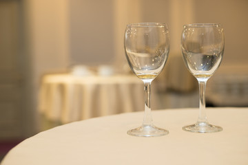 Two glasses with a drink stand on a neat table with a white tablecloth in the dining room