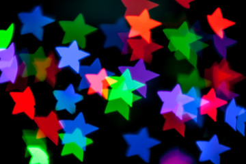 Blurred background with colorful bokeh star shaped lights on dark background/blurred Christmas lights