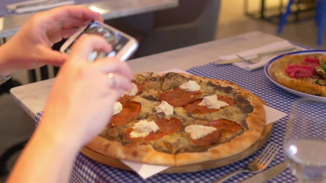 Woman taking photos of pizza by smartphone in 4k slow motion 60fps