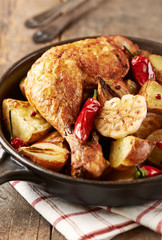 Oven-baked chicken with vegetables and fresh herbs. Homemade food. Symbolic image. Concept for a tasty and hearty dish. Rustic wooden background. Copy space.  