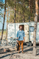 man holding acoustic guitar and standing at trailer with bicycle