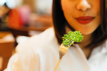 Asian women smile when she eating green vegetable,eating Parsley by fork,Asian eating vegetable for...