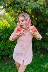 Beautiful young woman with pink hair holding two slices of watermelon