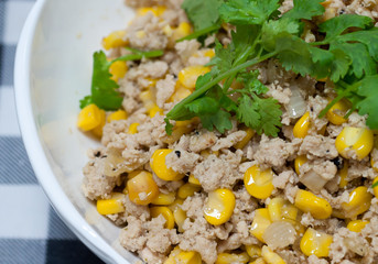 Minced pork corn salad  in white bowl on fabric pattern background