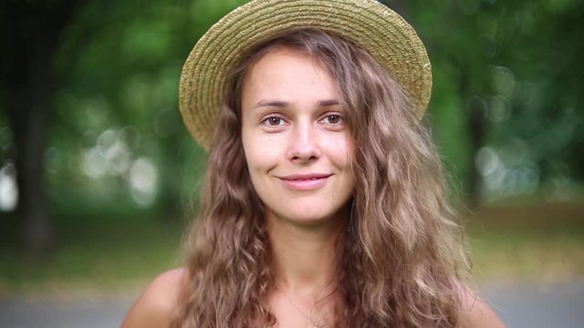 portrait of a beautiful positive long-haired girl with long hair in a hat on nature.