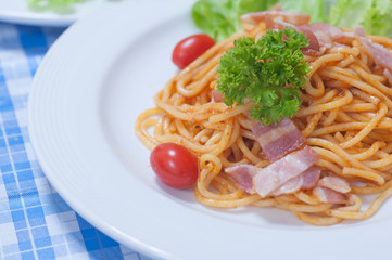 close up of delicious spaghetti with bacon and tomatoes on white plate and , Select focus