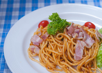 close up of delicious spaghetti with bacon and tomatoes on white plate and , Select focus