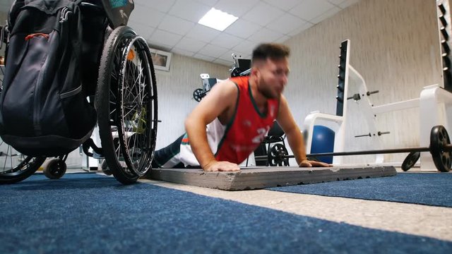 Handsome disabled man doing push ups in the gym during training.