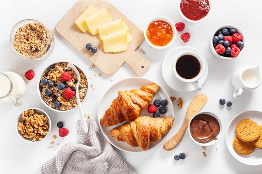 healthy breakfast with granola, berry, nuts, croissant, jam, chocolate spread and coffee. Top view