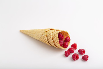 Ice cream or delicious dessert made from fresh raspberry berries on white background. Raspberry in a waffle cone. Summer, freshness, and the concept of the sweet menu.
