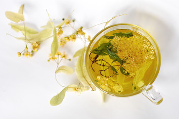 Photo of herbal tea in a transparent cup. flowers and leaves of herbs. flowers of linden and elderberry, leaves of mint. time for relaxation. hot tea. use for background, text, for your design, card