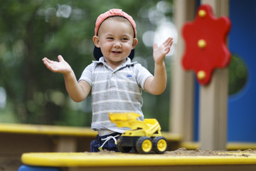 toddler playing with yellow toy car in sandbox