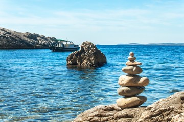 Pile of pebbles on the sea front on a beautiful day. Pebble stack on the seashore. Stone pyramid. Balanced Zen stones.