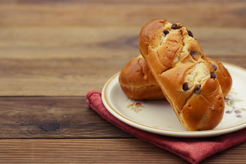 Traditional Buns with chocolate chips, breakfast or snack, rustic wood table.