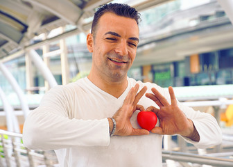 Handsome man show his emotion by raise heart up on his hands