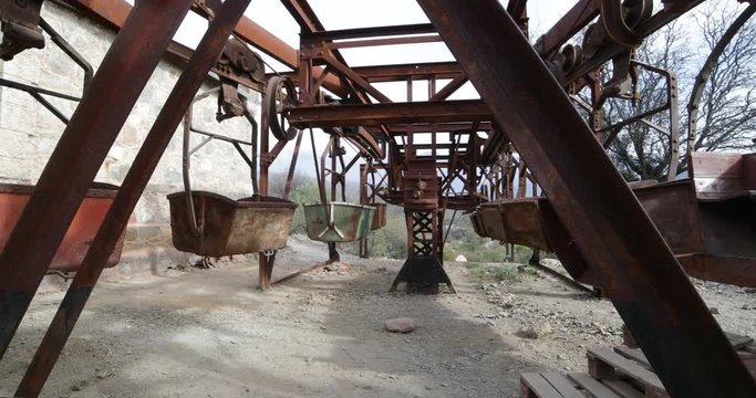 Second station of old Cable Car Chilecito-La Mejicana mine. Detail of iron wagons. Camera moves sideways showing the linear disposition of hanging wagons. La Rioja