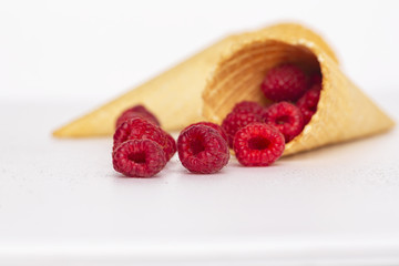 Ice cream or delicious dessert made from fresh raspberry berries on white background. Raspberry in a waffle cone. Summer, freshness, and the concept of the sweet menu.