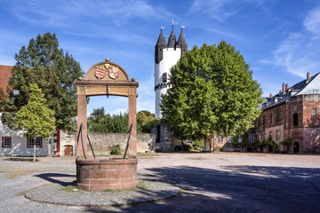 Germany, Rhine-Main area, Hanau, Steinheim: Old well in the center of the German town with castle park, famous white donjon tower, mansion, museum, medieval city wall and blue sky in the background.