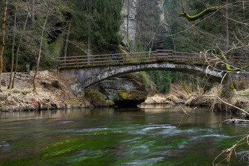 Fototapeta na wymiar Quiet spring river in the forest with old bridge