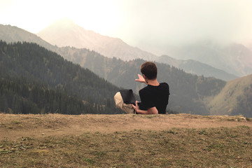 Naklejka na ściany i meble Freelancer young man lying and working with laptop in mountains
