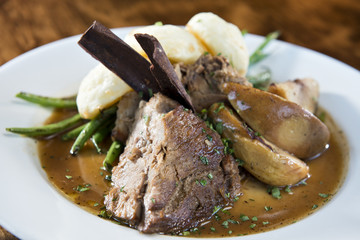 Braised Pork Rib on White Plate with Potatoes, Dumplings and Green Beans
