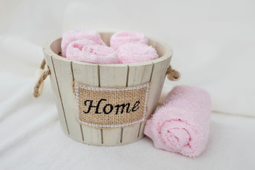 Set of pink towels in a wooden decorative bucket with the inscription 